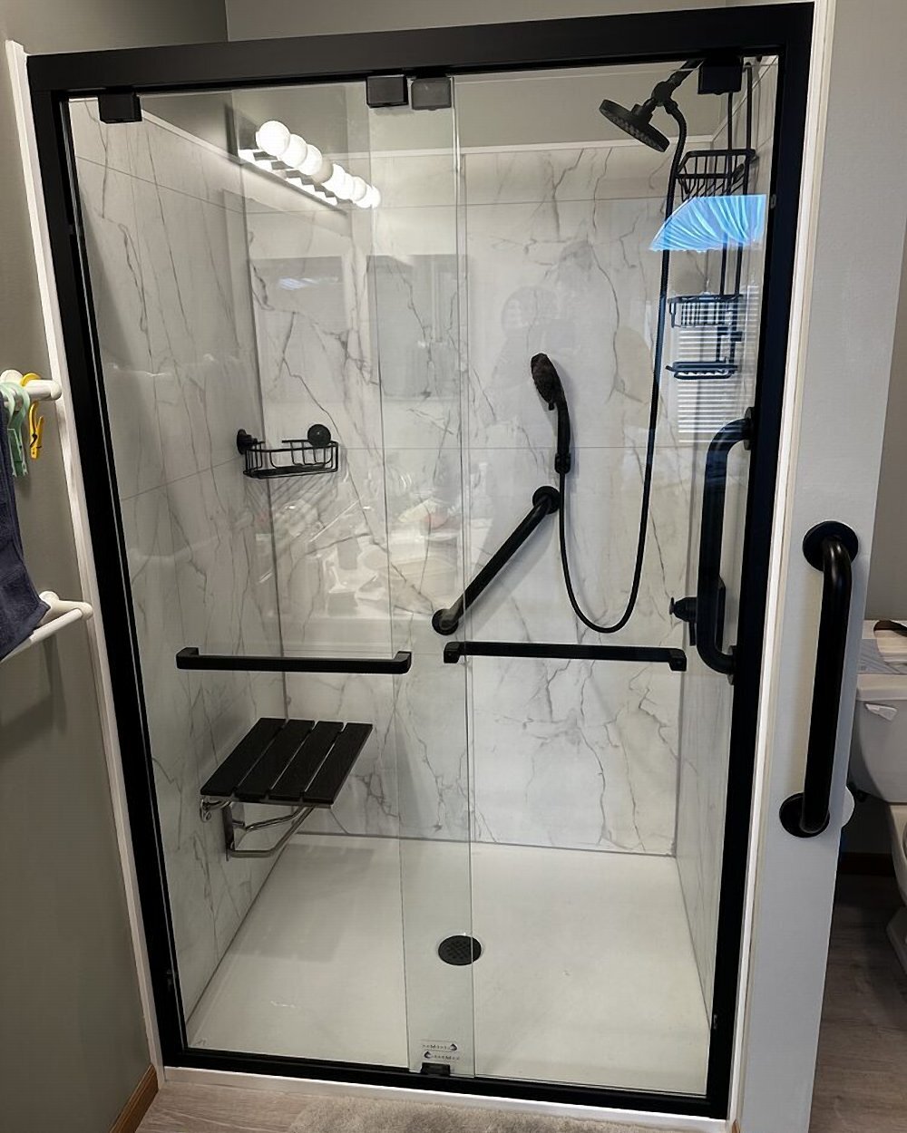 Bianco marble shower install by Made New Home Solutions with fold-down bench and bypass glass