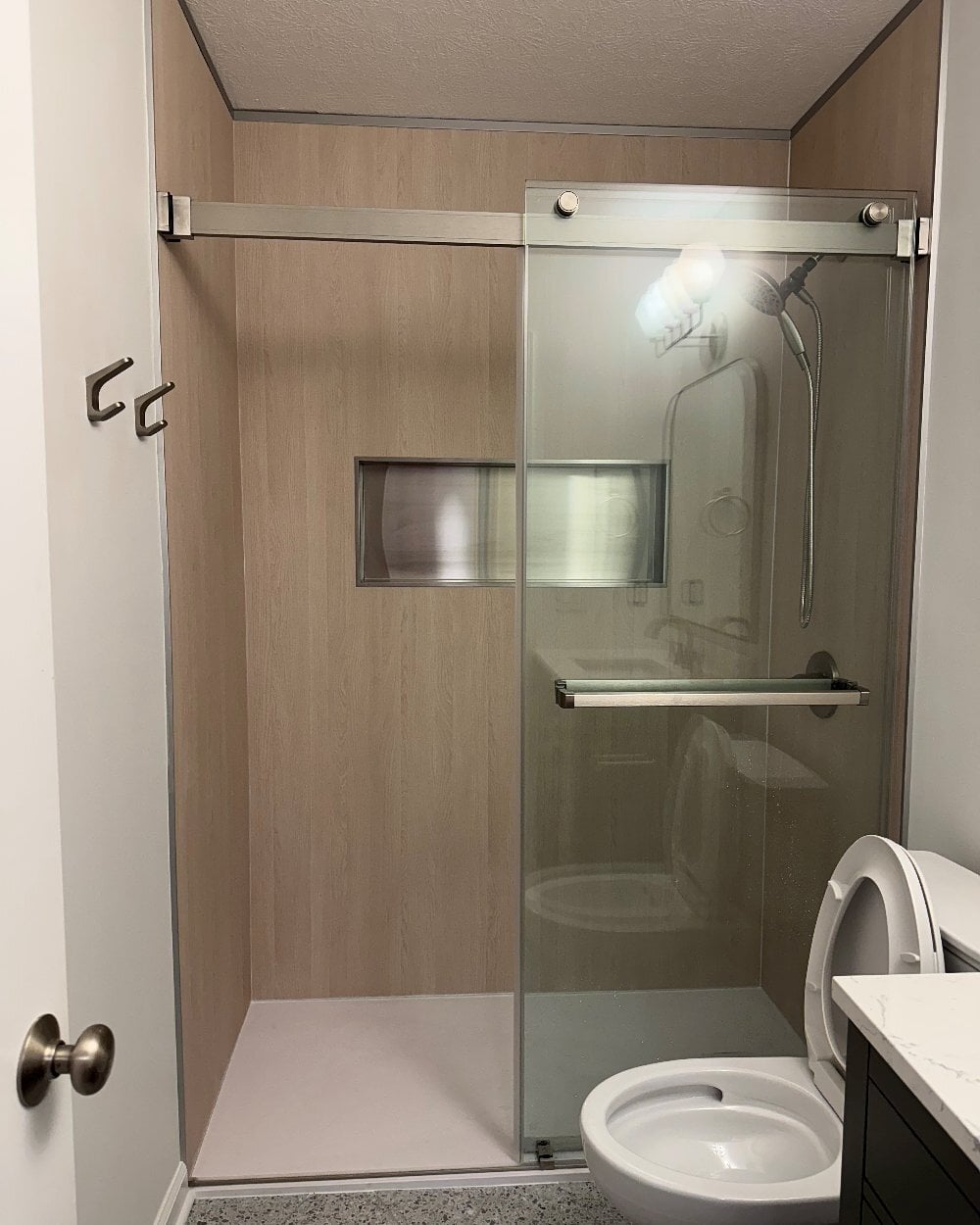 Light wood tub-to-shower install by Made New Home Solutions with bypass glass
